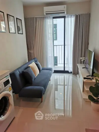 Modern living room with sleek sofa, TV, and washing machine near balcony in stylish apartment.