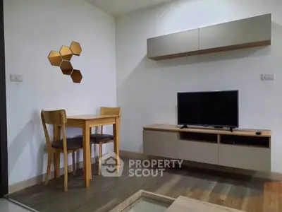 Modern living room with stylish furniture and wall decor, featuring a TV and dining area.