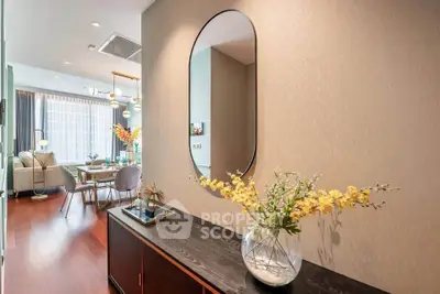Stylish modern living room with elegant decor and open dining area, featuring a large mirror and floral arrangement.