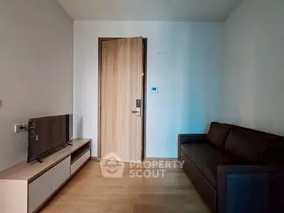 Cozy living room with modern sofa and TV unit, featuring wooden flooring and a sleek door.
