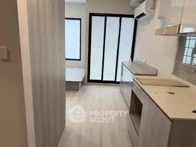Modern minimalist kitchen with sleek cabinetry and large windows for natural light.