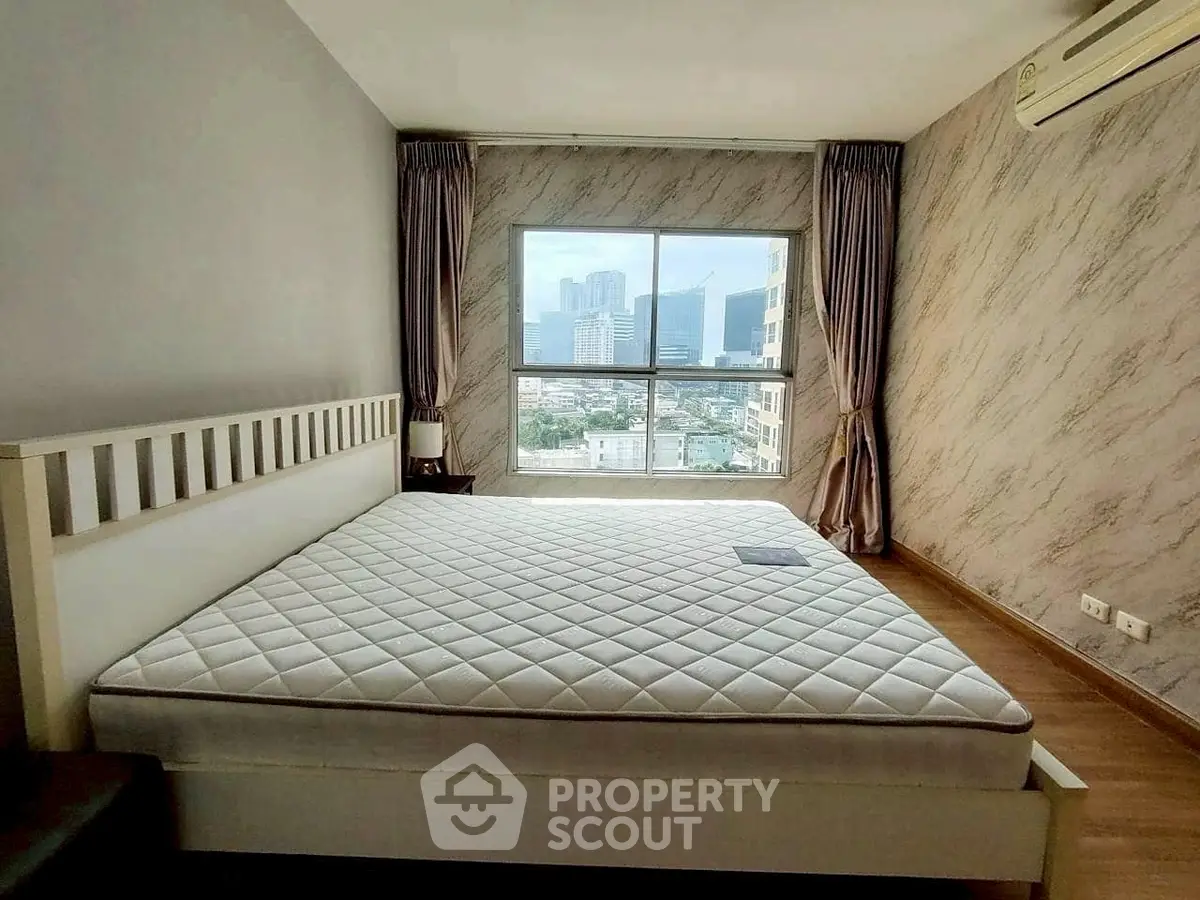 Spacious bedroom with large window offering stunning city view and modern decor.