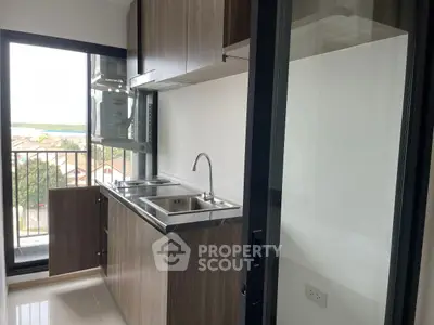 Modern kitchen with sleek cabinetry and balcony view in urban apartment