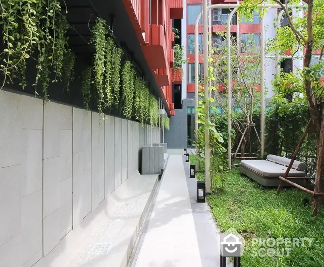 Modern garden area with lush greenery and stylish outdoor seating in urban residential complex.