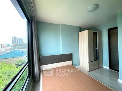 Bright bedroom with large window and city view, featuring modern wardrobe and sleek flooring.
