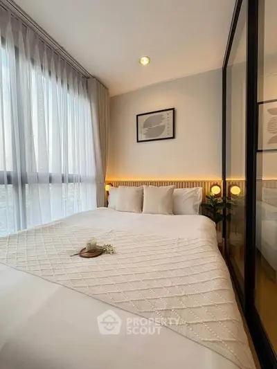 Cozy bedroom with large window and elegant decor, perfect for relaxation and comfort.