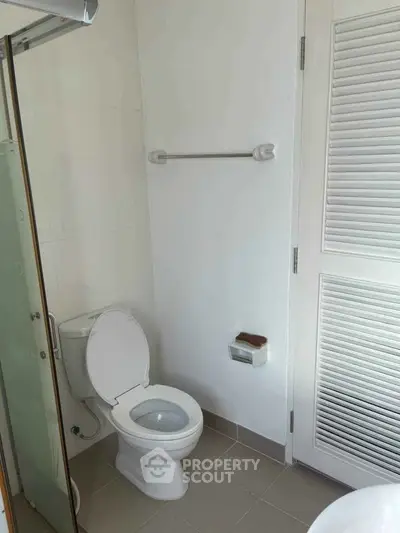 Modern bathroom with white fixtures and a glass shower door, featuring a sleek design.