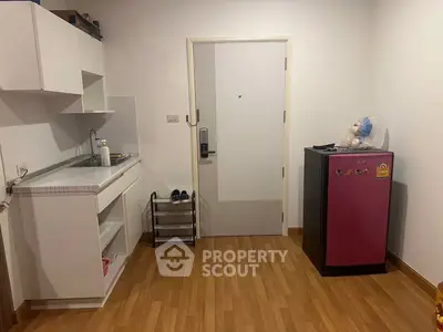 Compact kitchen area with pink fridge and wooden flooring