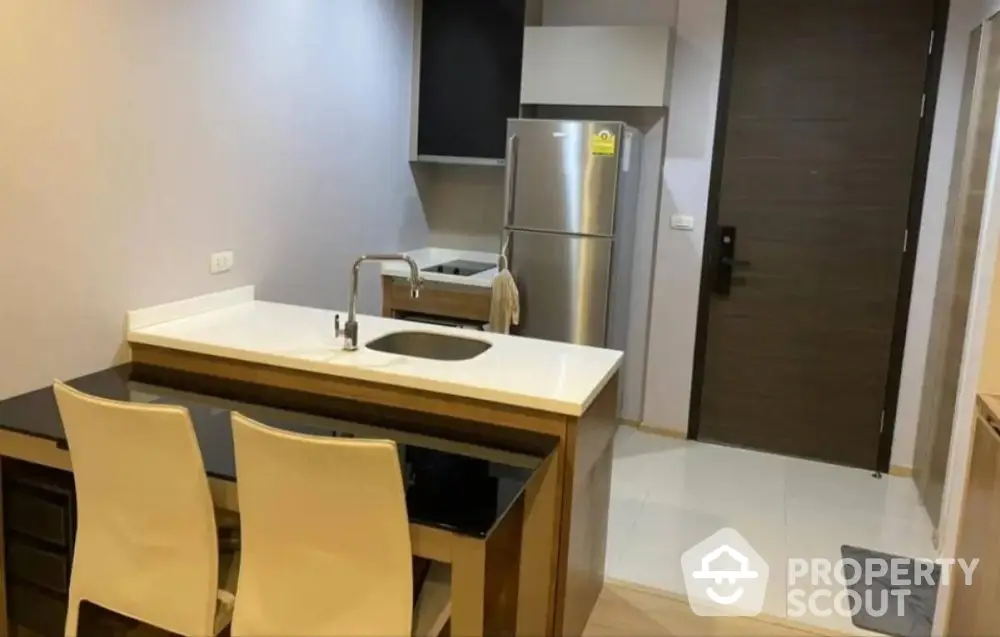 Modern kitchen with sleek design and stainless steel fridge in compact apartment