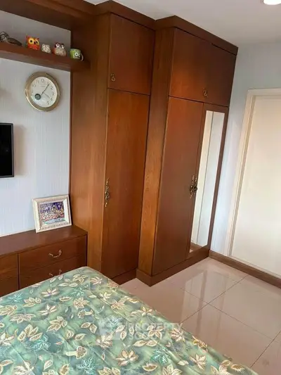 Cozy bedroom with wooden wardrobe and floral bedspread, perfect for a serene retreat.