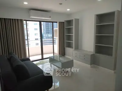 Modern living room with sleek furniture and large windows offering city views.