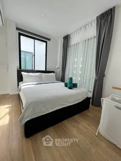 Modern bedroom with natural light and stylish decor in a cozy apartment.