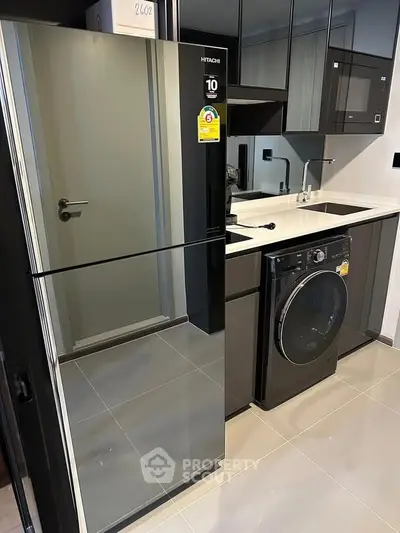 Modern kitchen with sleek appliances including fridge and washing machine, glossy cabinets, and stylish design.