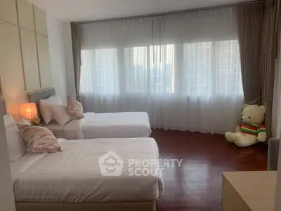 Spacious bedroom with twin beds and large windows in a modern apartment