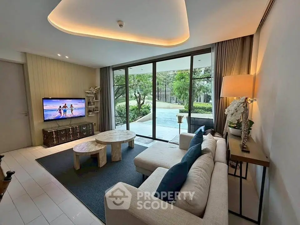 Modern living room with large windows and garden view, featuring stylish furniture and ambient lighting.