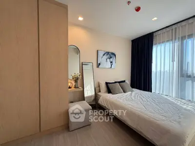 Modern bedroom with stylish decor and large window offering natural light