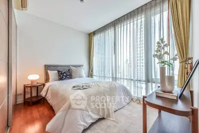 Luxurious bedroom with floor-to-ceiling windows and elegant decor in a high-rise apartment.
