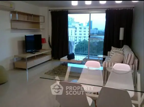 Modern living room with glass dining table and city view balcony.