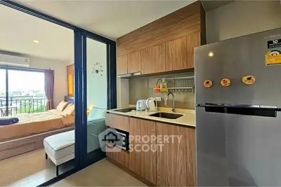 Modern studio apartment with compact kitchen and cozy bedroom, featuring sleek appliances and a bright ambiance.