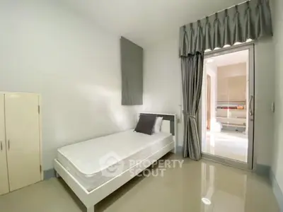 Minimalist bedroom with single bed and large window for natural light.