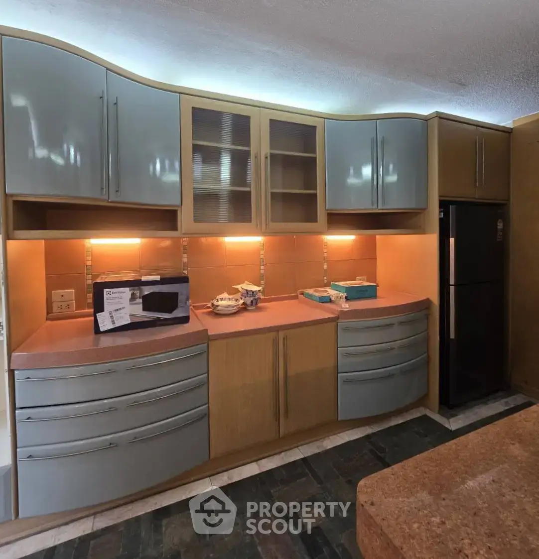 Modern kitchen with sleek cabinetry and under-cabinet lighting, featuring a black refrigerator and ample counter space.