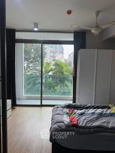 Spacious bedroom with large window and balcony view in modern apartment