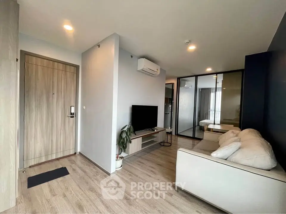 Modern living room with sleek design, featuring a cozy sofa, wall-mounted TV, and mirrored wardrobe.
