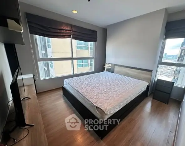 Spacious bedroom with large windows and modern furnishings in a high-rise apartment.