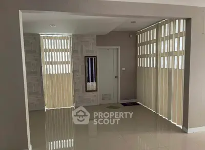 Spacious interior with modern vertical blinds and glossy tiled flooring, ideal for versatile living space.
