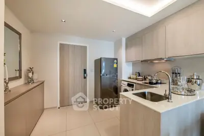 Modern kitchen with sleek cabinetry, stainless steel fridge, and washing machine in compact layout.