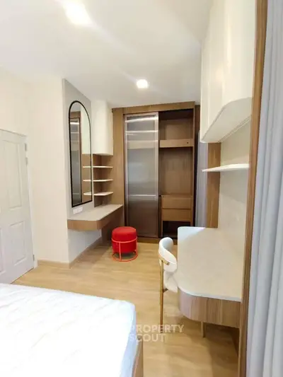 Modern bedroom with built-in wardrobe and stylish study area, featuring sleek wooden finishes and contemporary design.