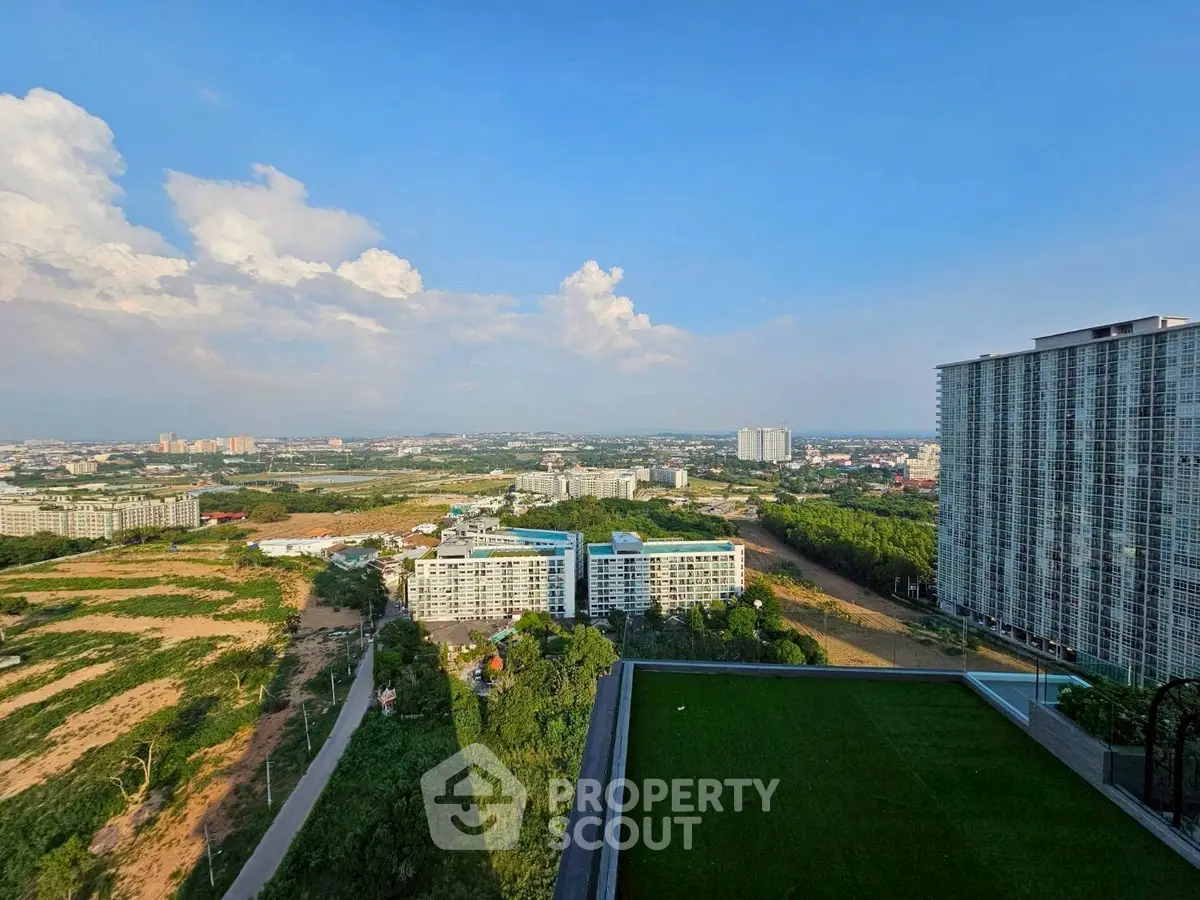 Stunning high-rise view of urban landscape with lush greenery and modern buildings under a clear blue sky.