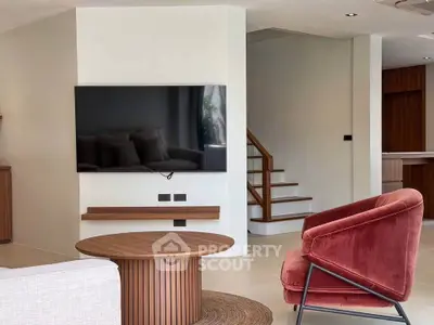 Modern living room with stylish furniture and wall-mounted TV, featuring a cozy red armchair and wooden accents.
