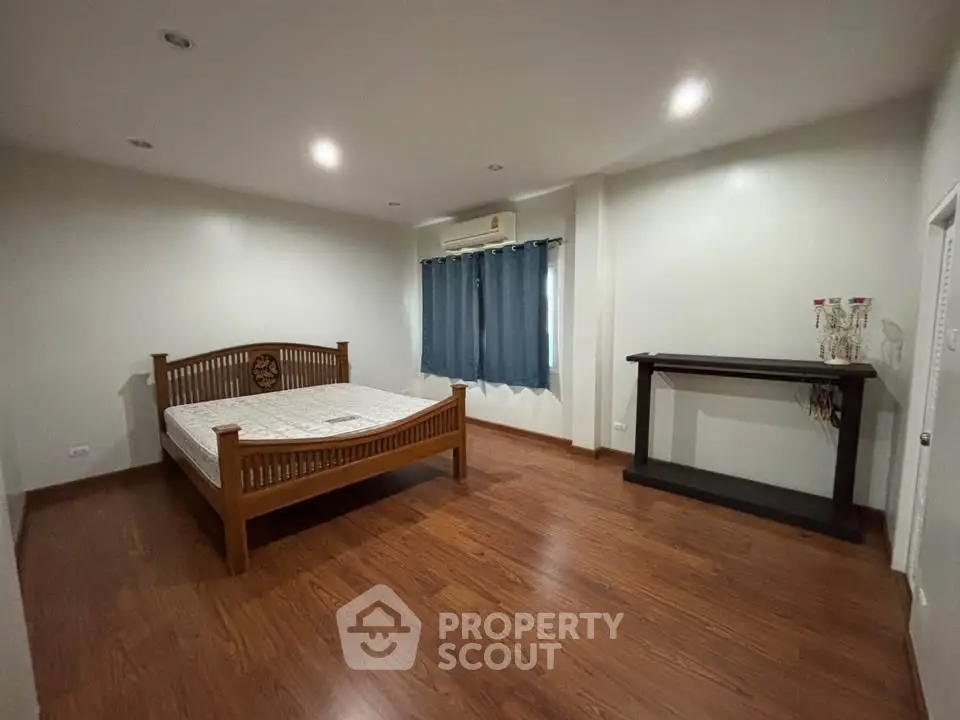 Spacious bedroom with wooden flooring and elegant furniture in modern home.