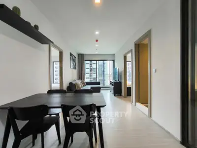 Modern open-plan living room with dining area and city view, featuring sleek furniture and neutral tones.