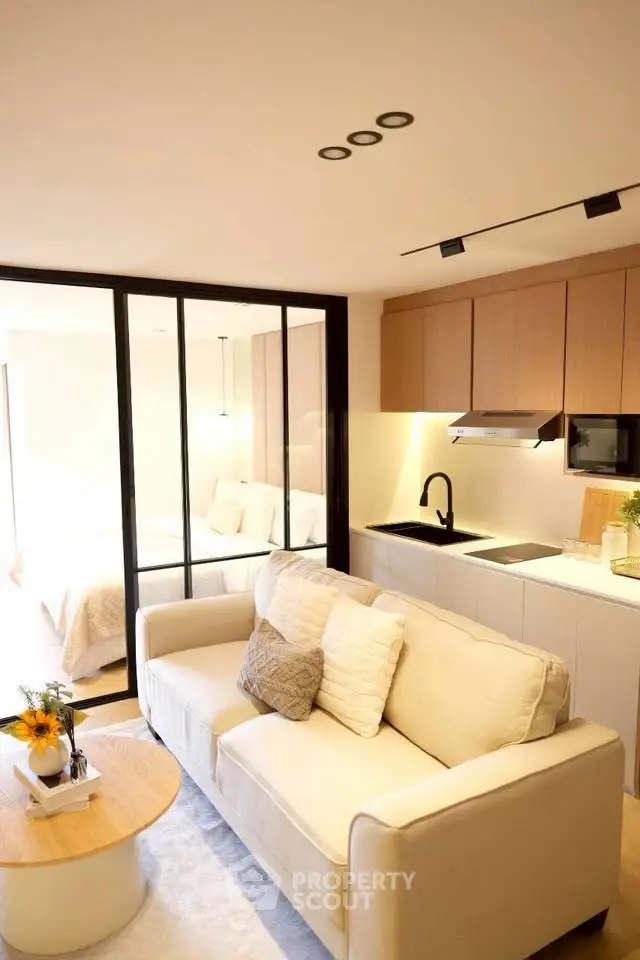 Modern open-plan living room with cozy sofa and sleek kitchen in stylish apartment.