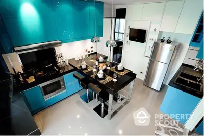 Sleek modern kitchen with high-gloss turquoise cabinetry, stainless steel appliances, and a black countertop island in a luxurious home.