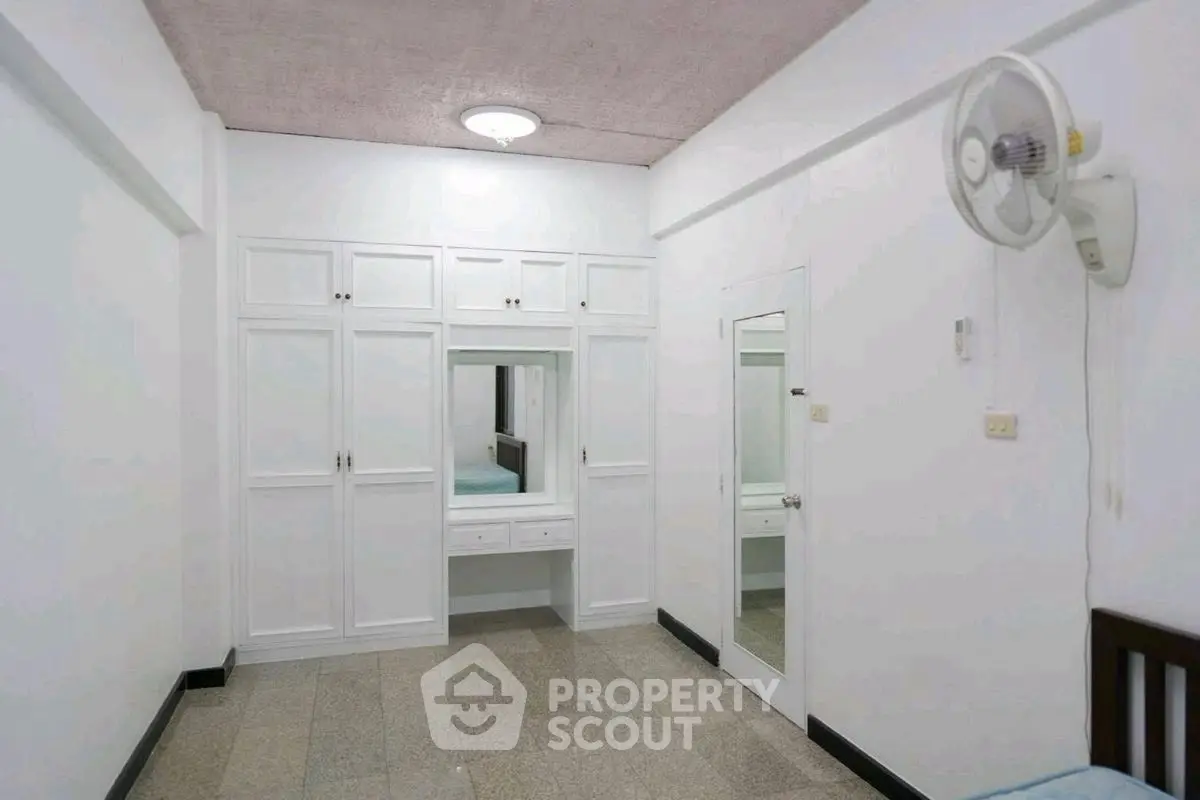 Spacious bedroom with built-in wardrobe and ceiling fan