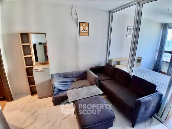 Modern living room with cozy sectional sofa and marble flooring, adjacent to a bedroom with natural light.