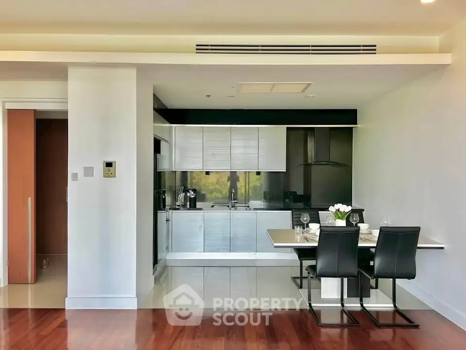 Modern kitchen with sleek cabinetry and dining area in open layout apartment.