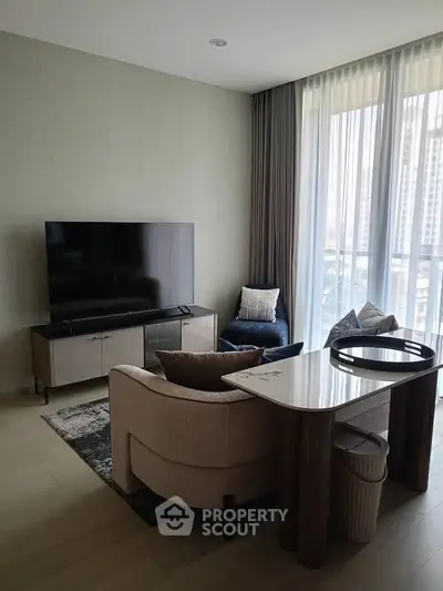 Modern living room with large TV, stylish furniture, and floor-to-ceiling windows offering city views.