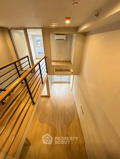 Modern loft-style apartment with high ceilings and wooden flooring, featuring a mezzanine and large windows for natural light.