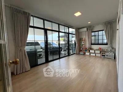 Spacious living room with large windows and wooden flooring, perfect for family gatherings.