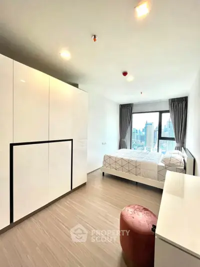 Modern bedroom with city view, sleek white wardrobe, and cozy decor