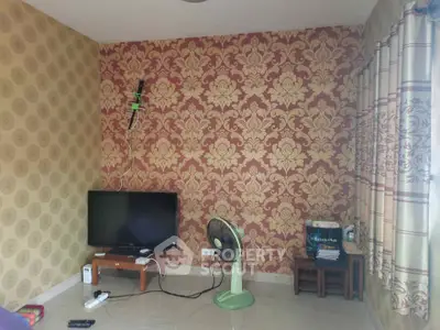 Charming living room with vintage wallpaper and natural light, featuring a cozy TV setup and elegant curtains.