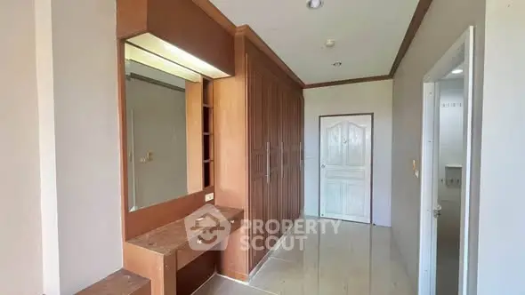 Spacious hallway with built-in wooden wardrobe and vanity in modern apartment.