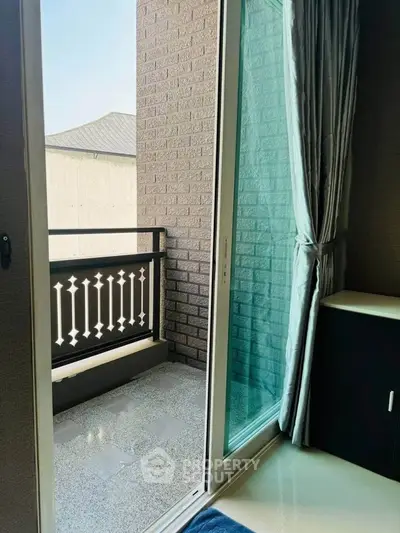 Charming balcony view from modern interior with sliding glass door and elegant curtains.