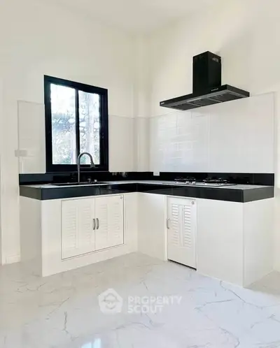 Modern kitchen with sleek black countertops and gas stove in a bright, minimalist design.