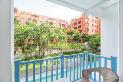 Charming balcony view overlooking lush garden and modern apartment complex.