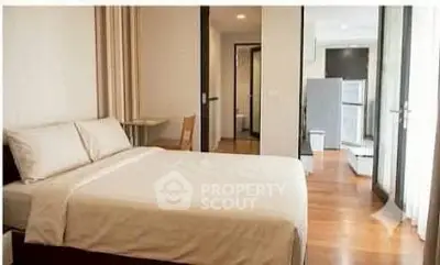 Modern bedroom with wooden flooring and open view to kitchen area
